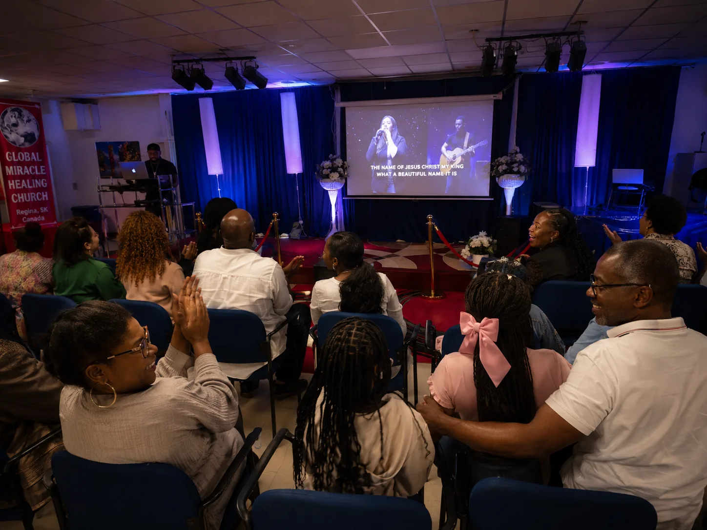 Congregation smiling, clapping, and worshipping together at Global Miracle Healing Church