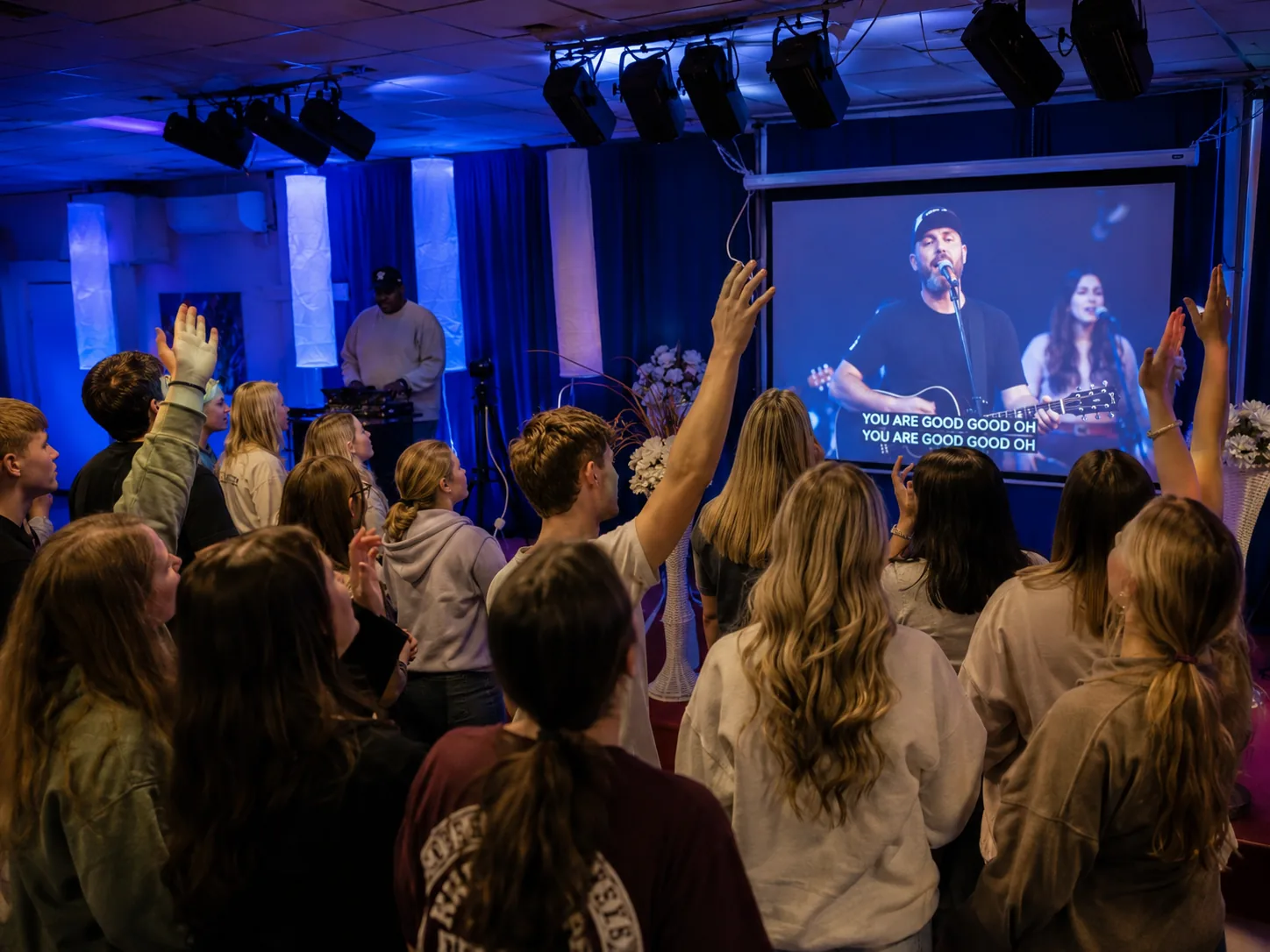 Young adult congregation worshipping with hands raised